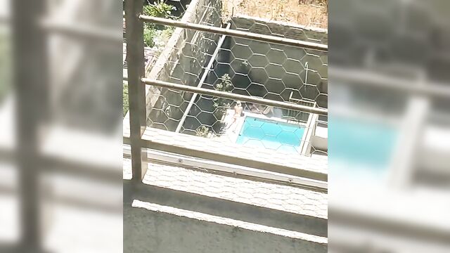 A girl in thong bikini sunbathes near the neighbor’s house